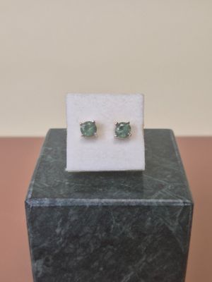 pair of emerald stud earrings on display on a marble block