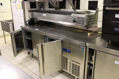 une cuisine avec de nombreux plans de travail et appareils électroménagers en inox