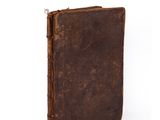 an old book with a brown cover sitting on top of a white surface