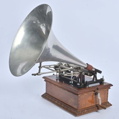 un gramophone argenté et noir posé sur un socle en bois