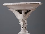 a statue of a bird on a pedestal with a bowl on it