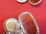 two small silver containers with lids on a red table