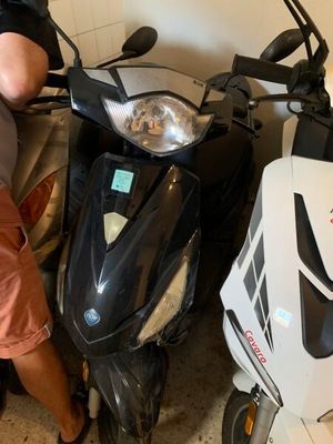 un homme debout à côté d'un scooter dans un garage