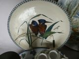 a plate with two birds painted on it next to a cup and saucer