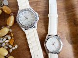 deux montres posées sur une table en bois, à côté de quelques perles