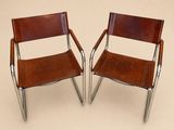 deux fauteuils en cuir marron aux pieds chromés, sur fond beige