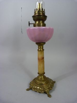 une lampe ancienne en laiton et en verre rose, surmontée d'une ampoule