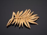 un gros plan d'une broche en feuille d'or posée sur une surface noire