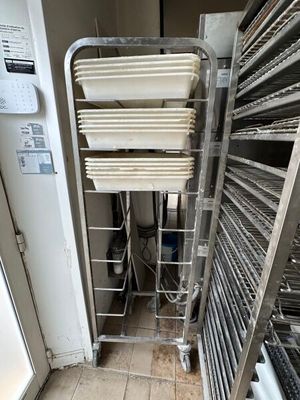 many trays of food on a rack in the kitchen