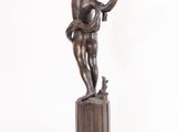 bronze statue of a boy holding a bird on a pedestal