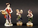 trois figurines représentant un homme et une femme portant des paniers de fruits