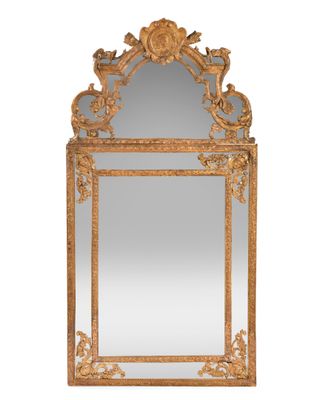 un miroir en or richement décoré, dont le cadre est orné d'un motif d'oiseau