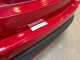 the rear end of a red car with a sticker on it ' s bumper