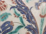 a close up of a vase with flowers and leaves on it