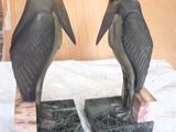 two statues of birds sitting on top of marble blocks