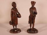 pair of wooden statues of a man and a woman holding baskets