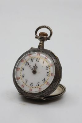 a silver pocket watch sitting on top of a white table