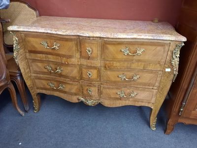 une commode avec un plateau en marbre et une chaise en osier à côté