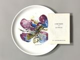 a white plate with a purple and blue flower on it