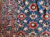 un tapis oriental posé sur un parquet, avec un chat endormi dessus
