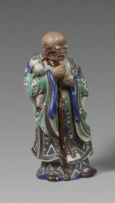 une vieille figurine représentant un homme barbu muni d'une canne