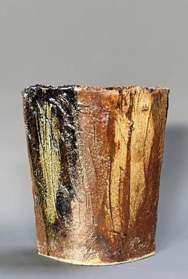 a brown and black vase sitting on a gray surface