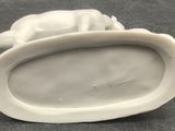 a white figurine of a cat on a plate