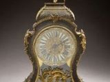 a clock with a statue on top of it on a table