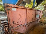 une benne rouge posée au milieu des bois