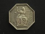 an image of a silver coin with a lady holding a scale
