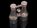 pair of antique silver plated binoculars on black reflective surface