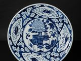 a blue and white plate with a design of flowers and birds on it