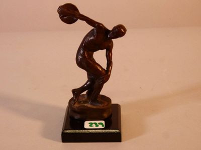 une statue en bronze représentant un homme en train de lancer un ballon de basket