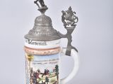 a beer mug with a statue on top of it