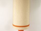an orange table lamp with a beige shade on top of it
