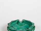 une photo d'un cendrier en verre vert posé sur une table blanche