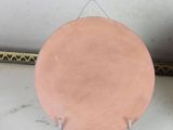 a pink plate sitting on a metal stand next to a plant