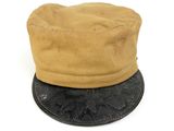 beige hat with black leather brimle on top of it on a white surface