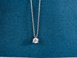 un pendentif en forme de diamant blanc est suspendu à une chaîne en argent sur un fond bleu