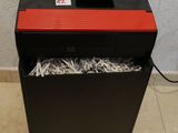 une déchiqueteuse de papier rouge et noire posée sur un sol carrelé