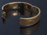 an image of a close up of a gold bracelet on a black surface