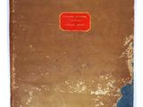 an old book with a red label on it sitting on a white surface