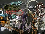 many different necklaces and bracelets laid out on a table