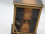 une petite horloge posée sur une surface blanche