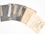 cinq vieux livres portant des inscriptions en chinois sur une surface blanche