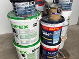 several buckets of paint are stacked on a pallet in front of a white wall