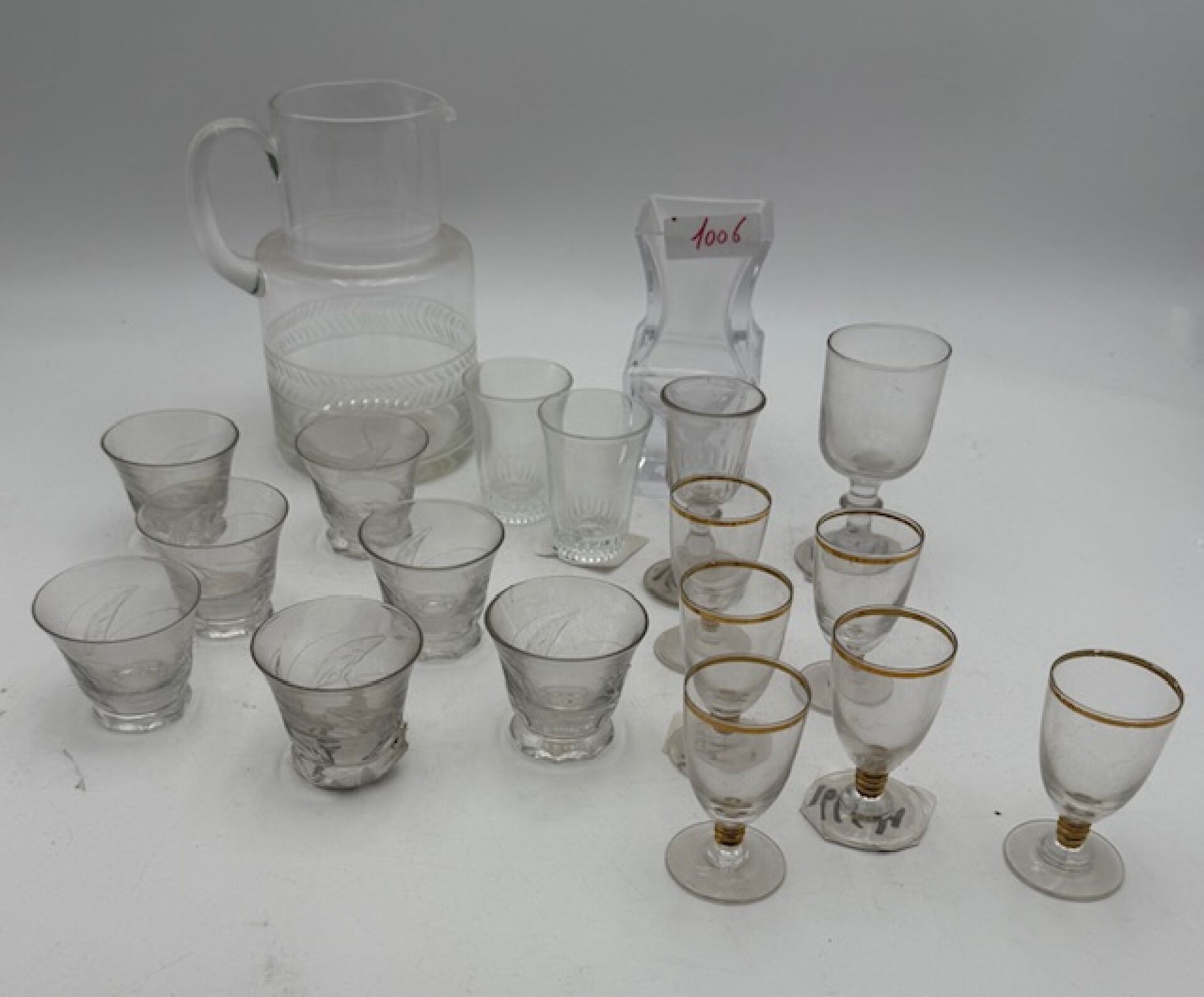 Un broc en cristal, sept verres à digestif en cristal taillé, six verres à porto en verre doré, deux verres et un vas...