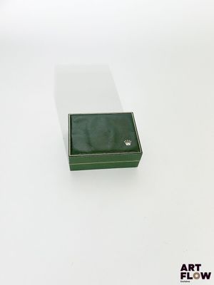 l'image d'une petite boîte verte posée sur une surface blanche