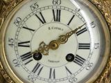 a gold clock with roman numerals on the face