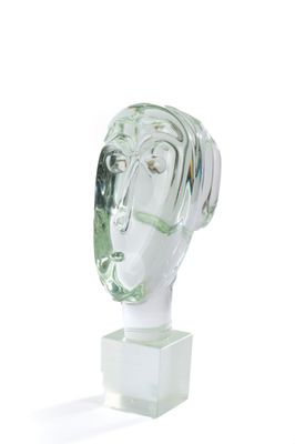 une sculpture en verre représentant la tête d'un homme, posée sur un socle transparent